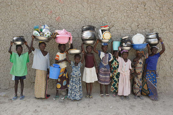Women and girls carrying pots and pans